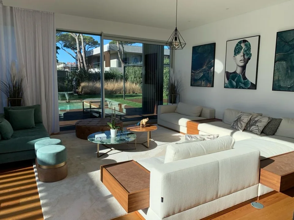 Sala luminosa com sofás, mesa de centro e portas envidraçadas para o jardim