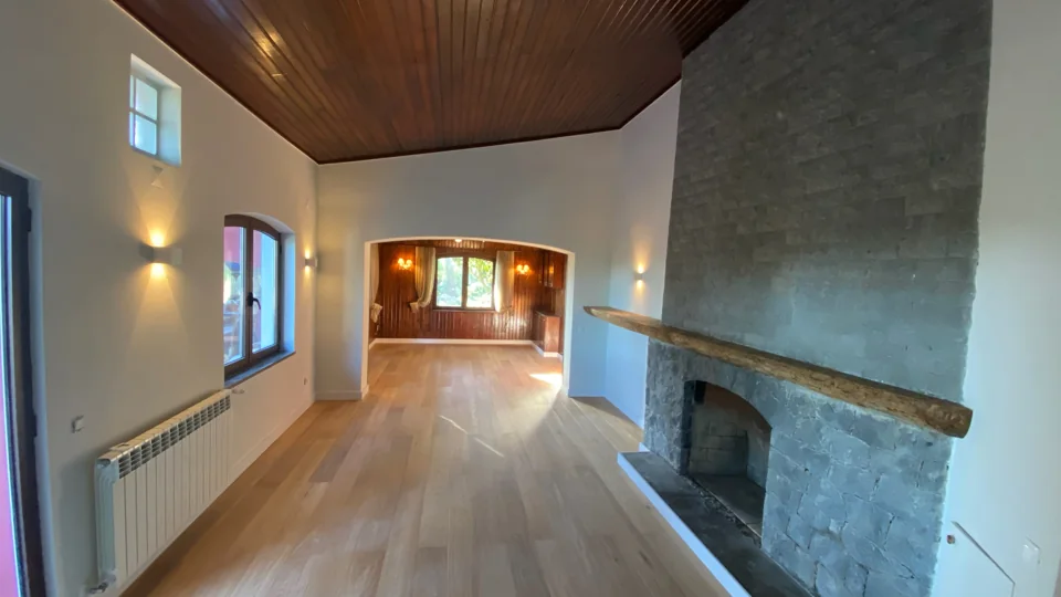 Sala após a intervenção, com pavimento de madeira, arco e lareira em pedra